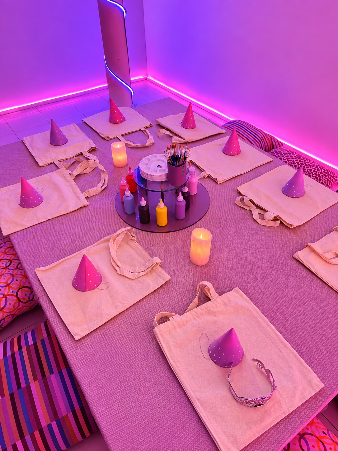 Montaje de mesa baja con tote bags, pinturas y gorritos de fiesta