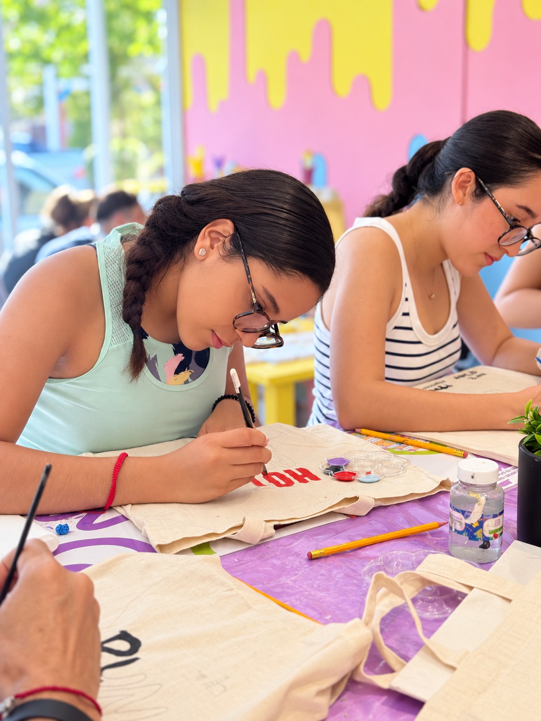 Amigas concentradas pintando tote bags en Art D'ler